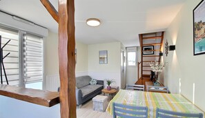 A cozy living area with a sofa, a dining table with chairs, and a bookshelf.