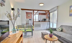A cozy living room with a sofa, a wooden coffee table, and a dining area with chairs and a table.