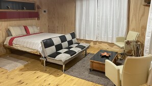 A cozy bedroom with a bed, a sofa, a chair, and a small table. - Cabañas Mi Refugio Puerto Varas (Puerto Varas)