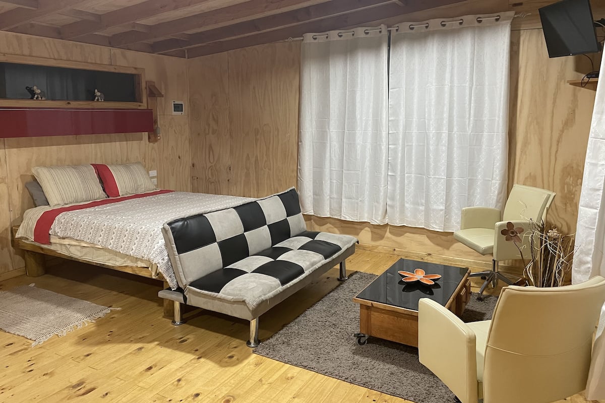 A cozy bedroom with a bed, a sofa, a chair, and a small table.