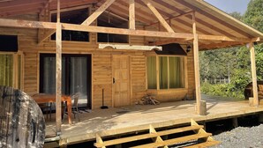 A wooden cabin with a covered porch, large windows, and a door. - Cabañas Mi Refugio Puerto Varas (Puerto Varas)