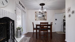 A dining area with a wooden table and chairs, a chandelier, and a clock on the wall. - Cozy Parkview Oasis With Gameroom (Amarillo)