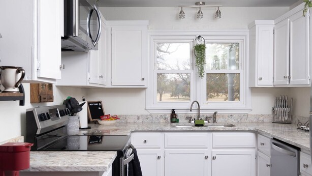 A modern kitchen with white cabinets, a built-in oven, a microwave, and a sink. - Cozy Parkview Oasis With Gameroom (Amarillo)