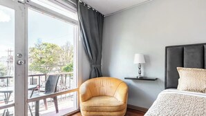 A hotel room with a large window, a sofa, a bed, and a bedside table with a lamp. - Blue house la floresta (Quito)