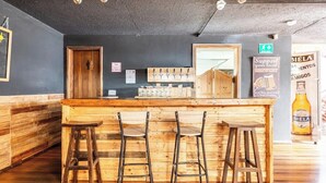 A bar area with wooden stools, a bar counter, and a beer tap. - Blue house la floresta (Quito)