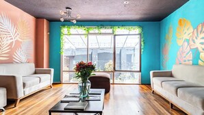 A modern living room with two sofas, a coffee table, and a large window with a view of greenery and buildings. - Blue house la floresta (Quito)