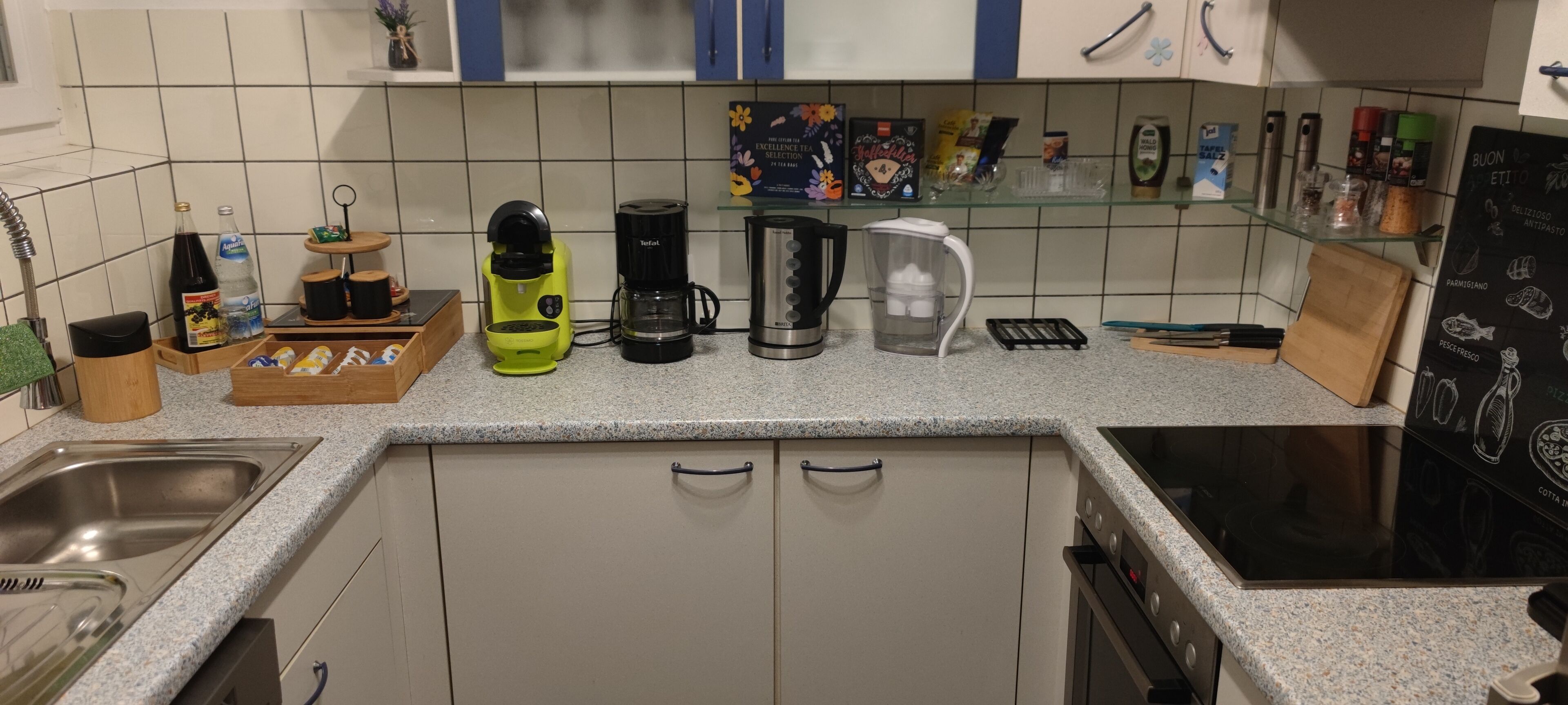 Eine Küche mit Granitabdeckung, einer Kaffeemaschine, einem Wasserkocher und verschiedenen Küchenutensilien.