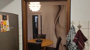 A kitchen with a refrigerator, a wooden dining table, chairs, and a hanging towel. - Vacation apartment 94 sqm & 16 sqm terrace - with magnificent panoramic views of the city and the Alps (Waldshut-Tiengen)