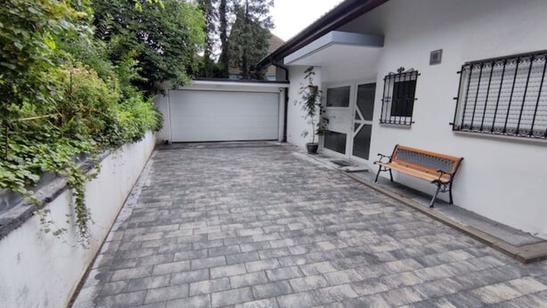 A paved courtyard with a bench, a garage door, and a potted plant. - Vacation apartment 94 sqm & 16 sqm terrace - with magnificent panoramic views of the city and the Alps (Waldshut-Tiengen)