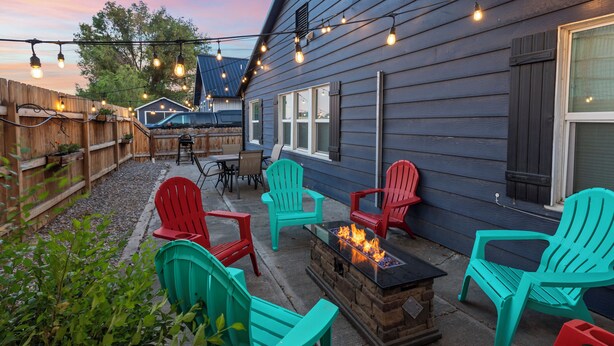 Eine Terrasse mit Adirondack-Stühlen, einem Feuerkorb und Lichterketten.