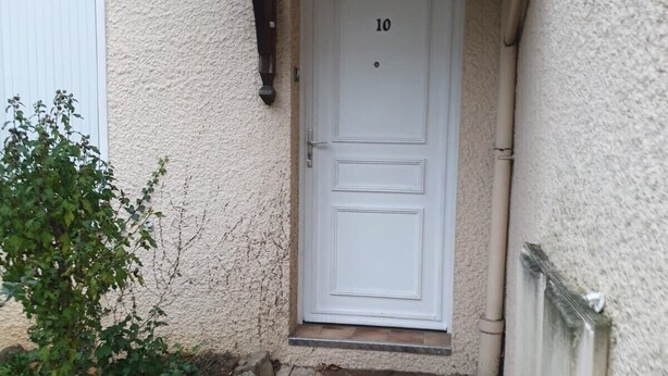 A white door with the number 10, a small overhang above it, and a concrete step leading up to the door. - Auberge Rose - Hostel (Noisiel)