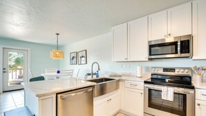 A modern kitchen with white cabinets, stainless steel appliances, and a dishwasher. - Cedar Key Condo w/ Balcony & Gulf Views! (Cedar Key)