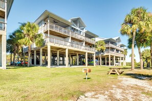 A beachfront hotel with multiple balconies, a covered outdoor area, and a picnic table. - Cedar Key Condo w/ Balcony & Gulf Views! (Cedar Key)