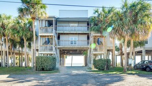 A multi-story building with balconies, palm trees, and a gravel driveway. - Cedar Key Condo w/ Balcony & Gulf Views! (Cedar Key)