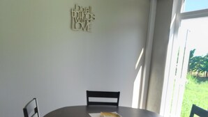 A dining area with a round table, four chairs, and a wall decoration. - Two Bedroom Apartment Rental (Paix Bouche)