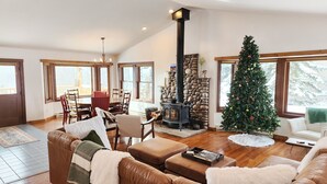 A cozy living room with a fireplace, a dining area, and a Christmas tree. - Large mountain home, incredible views, hot tub, game room, minutes from Jackson! (Jackson)