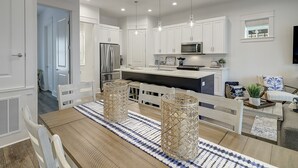 Une cuisine moderne avec des meubles blancs, des appareils en acier inoxydable et des luminaires suspendus.