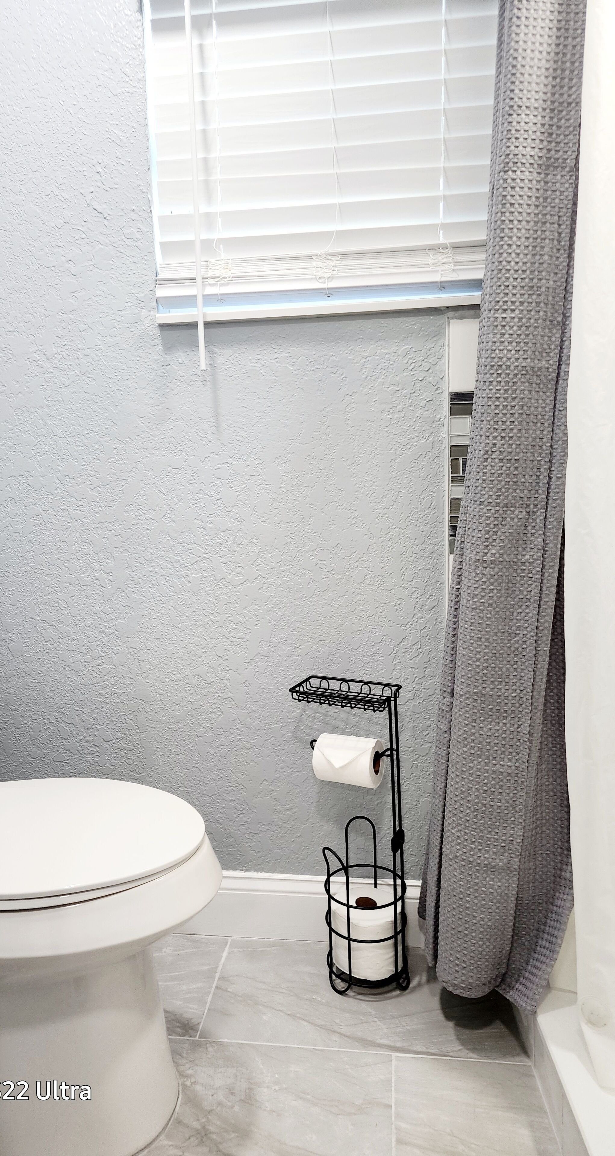 Un baño con inodoro, toallero y cortina de ducha.