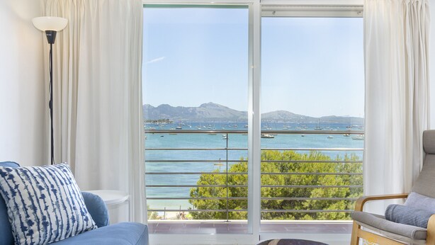 A room with a large sliding glass door leading to a balcony with a view of the sea and boats. - Apartamento Tonia by Mallorca North Villas (Port de Pollença)