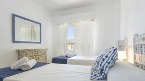 A hotel room with two beds, a large mirror, a view of the outdoors, and a rustic headboard. - Apartamento Tonia by Mallorca North Villas (Port de Pollença)