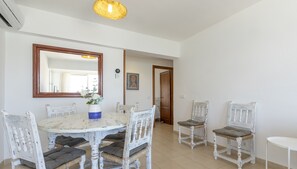 A dining area with a round table, white chairs, and a large mirror. There is a vase with flowers on the table. - Apartamento Tonia by Mallorca North Villas (Port de Pollença)
