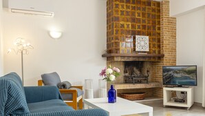 Ein Wohnzimmer mit Kamin, einer Couch, einem Fernseher und einer dekorativen Vase.