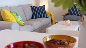 Ein modernes Wohnzimmer mit einem grauen Sofa, gestreiften Kissen, einer gelben Decke und einem kleinen Tisch mit einer dekorativen Muschel.