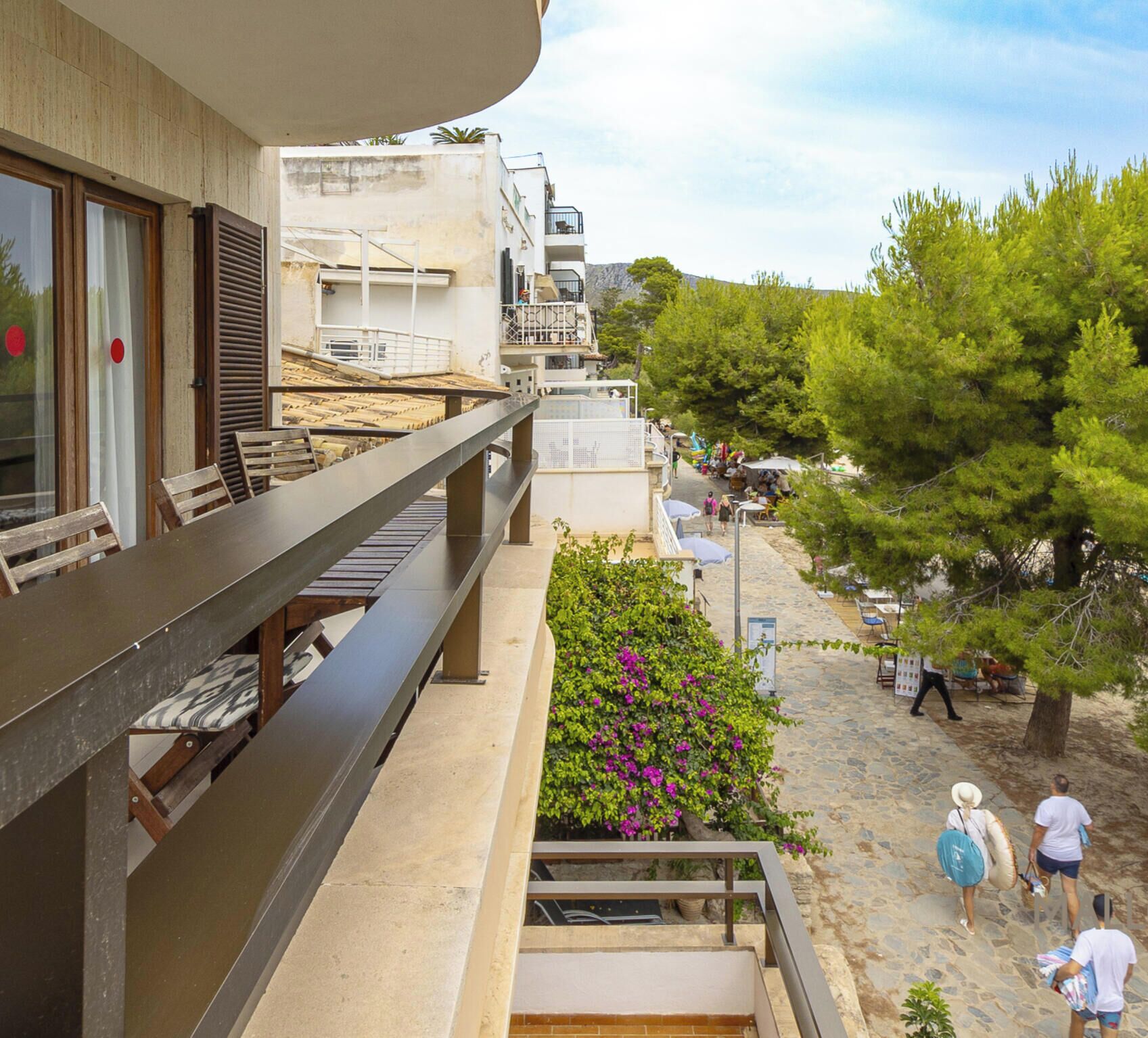 Balcony with outdoor furniture and open views over a tree-lined walkway next to the beach, in a quiet and pleasant area just a few steps from the sea.