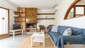 Ein Wohnzimmer mit blauem Sofa, weißem Couchtisch und Kamin an einer Ziegelwand.