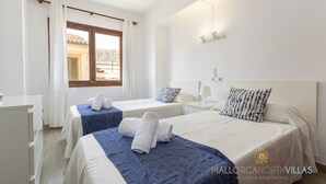 Ein Hotelzimmer mit zwei Betten, einem Schreibtisch und einem fenster mit Vorhängen.