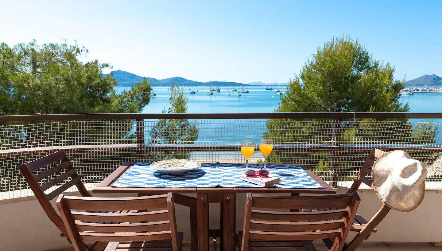 Ein Balkon mit Tisch für zwei Personen, mit Blick auf ein Gewässer und Boote.