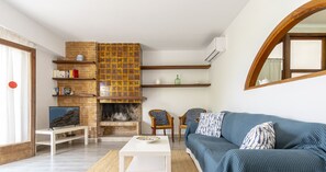 A living room with a blue sofa, white coffee table, and a fireplace with a brick wall.