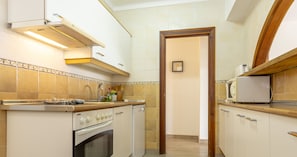 A kitchen with white cabinets, a built-in oven, a microwave, and a toaster.