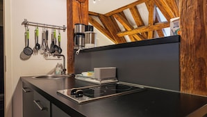 Eine Küche mit schwarzem Arbeitsplatz, Spüle aus Edelstahl und Holzbalken darüber.