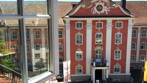 Ein rotes Gebäude mit weißem Dekor und einer Uhr an der Fassade.