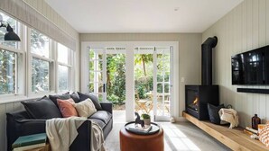 A modern living room with a black sofa, a round wooden coffee table, and a fireplace. - Beautiful Balmain East Cottage (Balmain East)