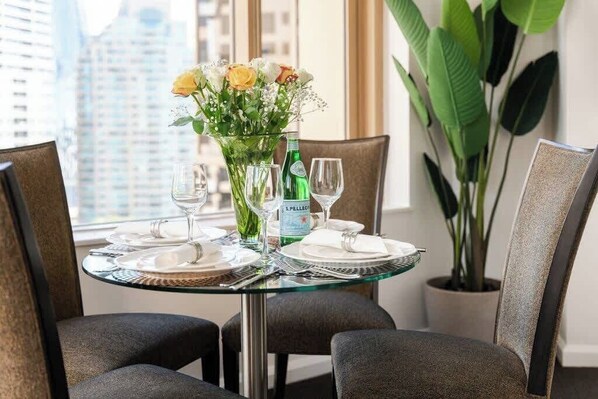 A dining table set for two with a vase of flowers, a bottle of champagne, and a city view. - At Home with Sydney Harbour Bridge and Opera House (The Rocks)