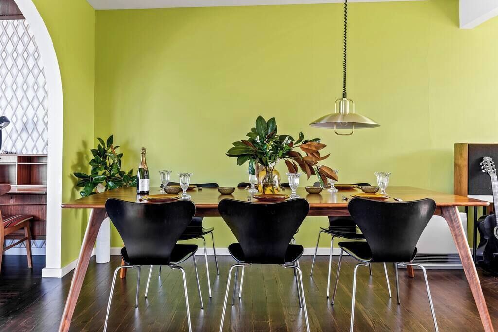 A dining area with a wooden table, black chairs, and a hanging lamp.