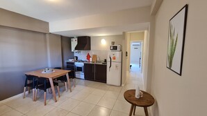 Una cucina compatta con angolo ristoro, forno a microonde, frigorifero e un piccolo tavolo con sedie.