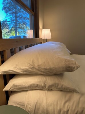 A bed with white bedding and a wooden headboard. - The Badger House (Wausau)