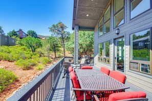 A deck with a table and chairs, surrounded by a wooden railing, overlooking a landscaped area with trees and shrubs. - Hot Tub + Deck: Mtn-View Pine Getaway! (Pine)