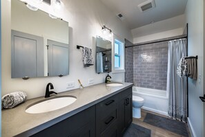 Une salle de bain avec deux lavabos, un grand miroir, une douche et des toilettes.