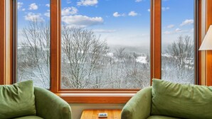 Habitación con un amplio ventanal que ofrece vistas a un paisaje nevado con árboles y cielo despejado.