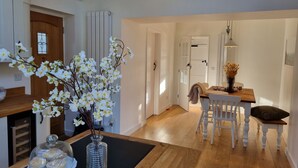 Een moderne keuken met witte kasten, een houten aanrechtblad en een vaas met witte bloemen.