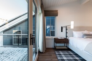 Ein Schlafzimmer mit Bett, Nachttisch, Lampe, Fenster und Blick ins Freie.