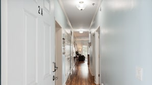 A hallway with white doors, wooden flooring, and a ceiling light fixture.