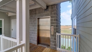 An elevator with a stone wall, a wooden deck, and a view of a field.