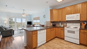 A modern kitchen with wooden cabinets, a white stove, and a dishwasher.