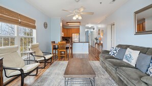 A spacious living area with a sofa, chairs, a dining table, and a kitchen in the background.