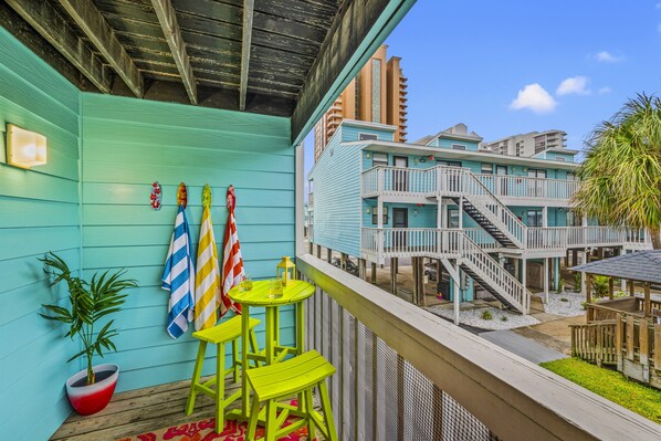 A balcony with a view of a multi-story building with a blue exterior and white railings.
